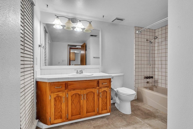 full bathroom featuring toilet, vanity, tiled shower / bath, and a textured ceiling