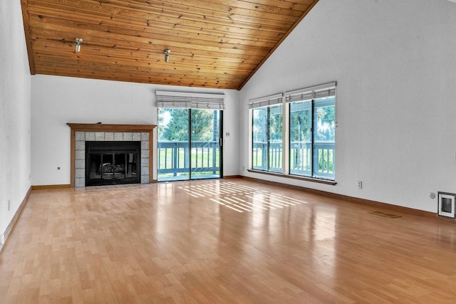 unfurnished living room featuring light wood-type flooring, a tiled fireplace, and wood ceiling