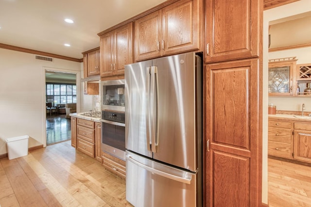 kitchen featuring ornamental molding, light wood-type flooring, appliances with stainless steel finishes, and sink