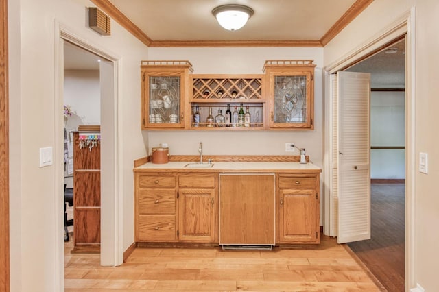 bar with light hardwood / wood-style flooring, sink, and crown molding