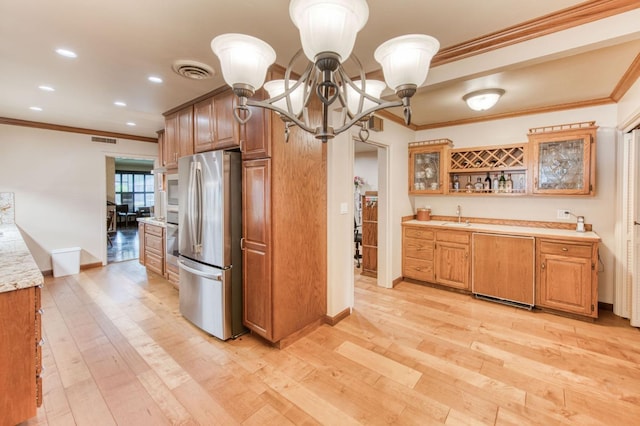 kitchen with stainless steel refrigerator, light hardwood / wood-style floors, and crown molding