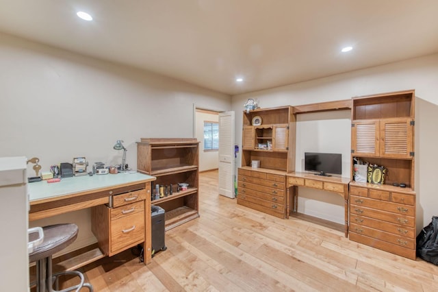 office space with built in desk and light wood-type flooring