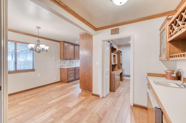 kitchen with ornamental molding, hanging light fixtures, sink, a chandelier, and light hardwood / wood-style flooring