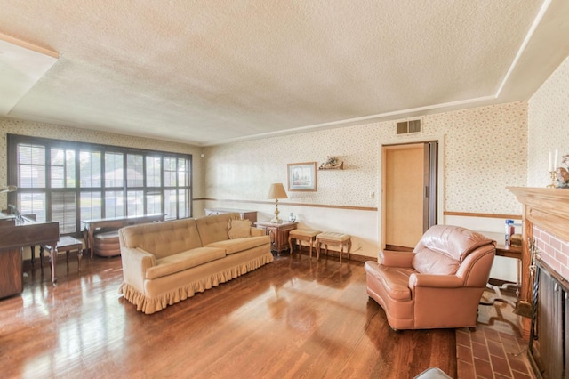 living room with a textured ceiling, hardwood / wood-style floors, and a brick fireplace