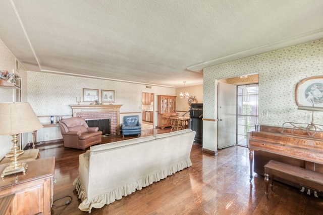 living room featuring hardwood / wood-style floors, a fireplace, a textured ceiling, and an inviting chandelier