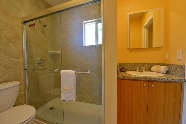 bathroom with toilet, vanity, and a shower with door