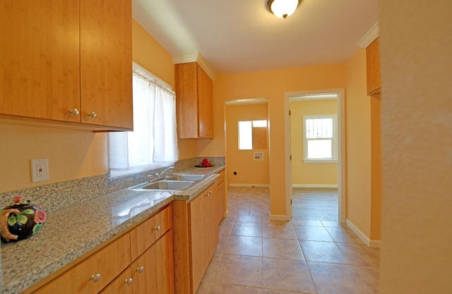 kitchen with light stone countertops, sink, and light tile patterned floors