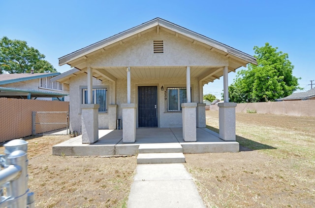 bungalow featuring covered porch and a front lawn