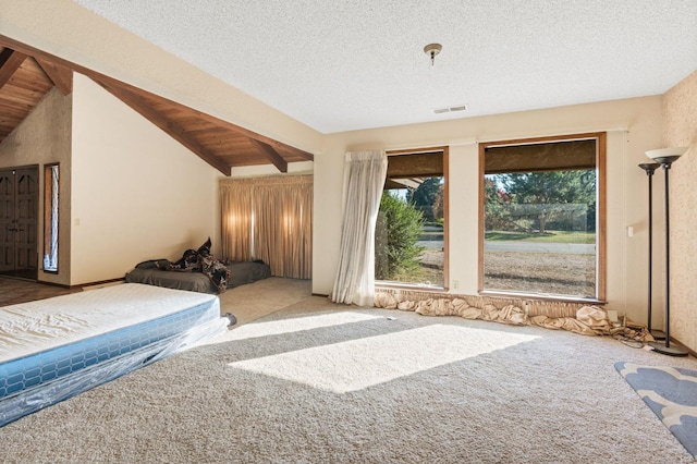 bedroom with carpet flooring, vaulted ceiling with beams, and a textured ceiling