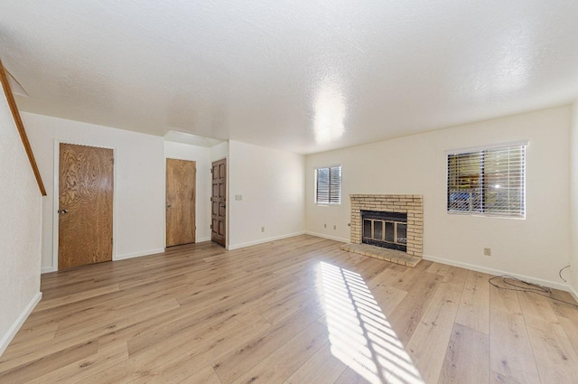 unfurnished living room with a fireplace, light hardwood / wood-style flooring, and a textured ceiling