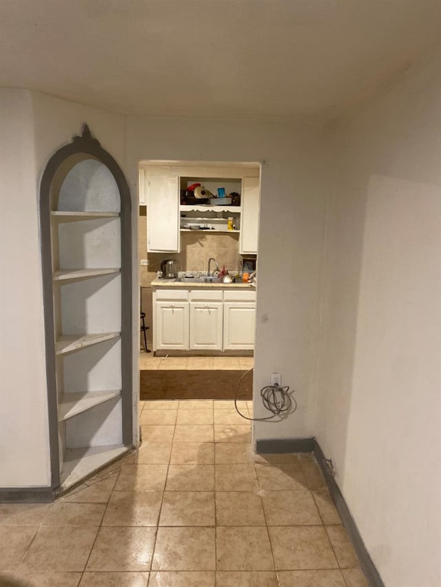 hall with light tile patterned floors and a sink
