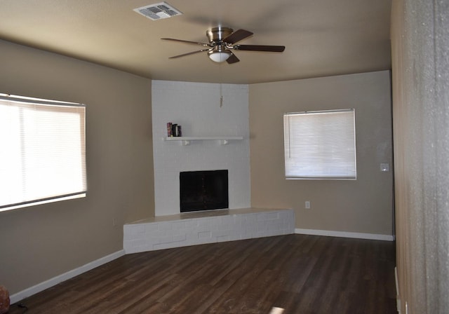 unfurnished living room featuring dark hardwood / wood-style floors, a brick fireplace, and ceiling fan