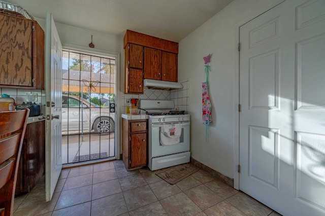 kitchen featuring brown cabinets, under cabinet range hood, and white gas range oven