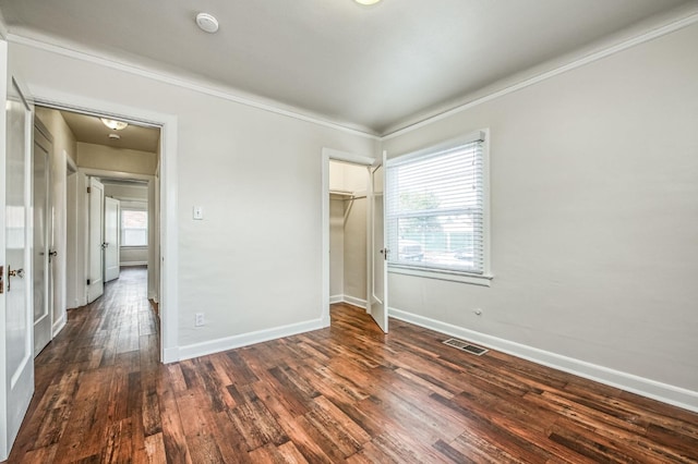 unfurnished bedroom with crown molding, dark hardwood / wood-style flooring, and a closet