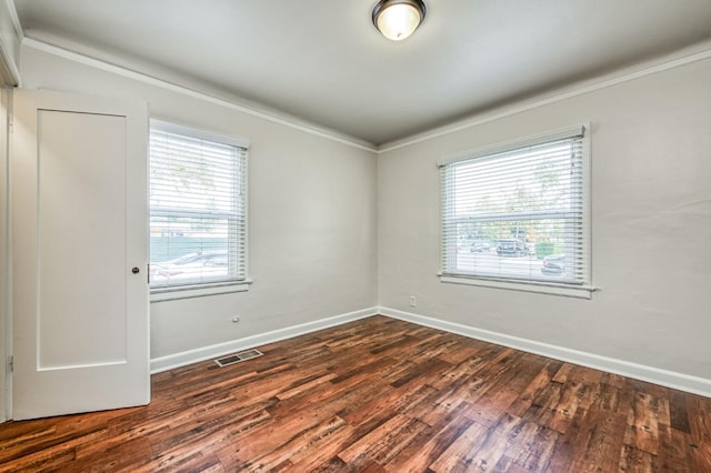 empty room featuring ornamental molding, plenty of natural light, and dark hardwood / wood-style flooring