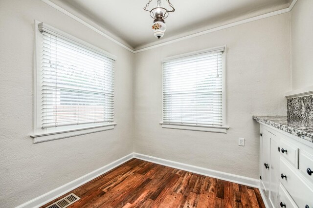 unfurnished dining area with dark hardwood / wood-style flooring and ornamental molding