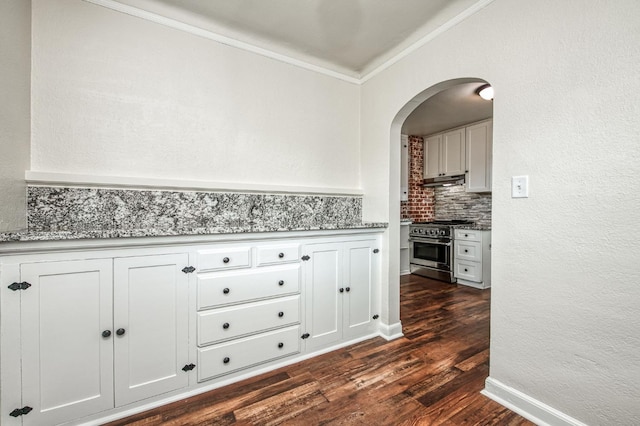 kitchen featuring crown molding, tasteful backsplash, dark hardwood / wood-style floors, high end stove, and white cabinets