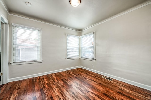 spare room featuring dark wood-type flooring, plenty of natural light, and crown molding