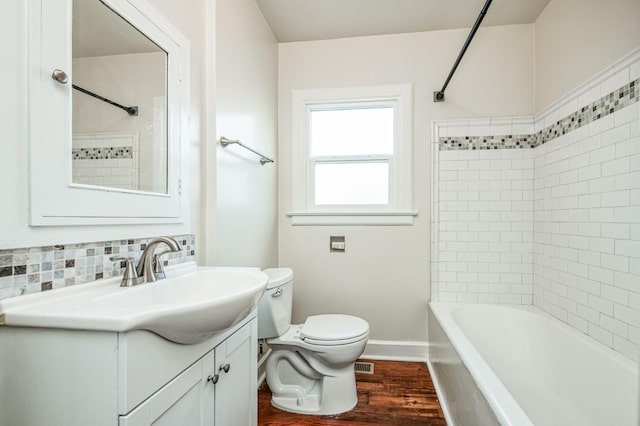 full bathroom featuring toilet, tasteful backsplash, tiled shower / bath, wood-type flooring, and vanity