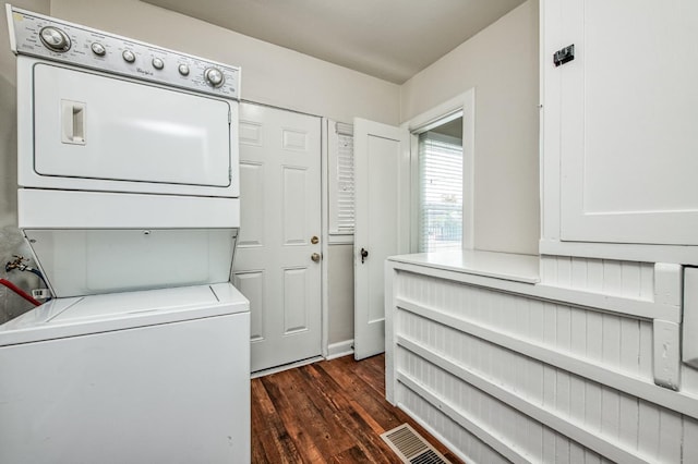 clothes washing area featuring stacked washer / drying machine and dark hardwood / wood-style flooring