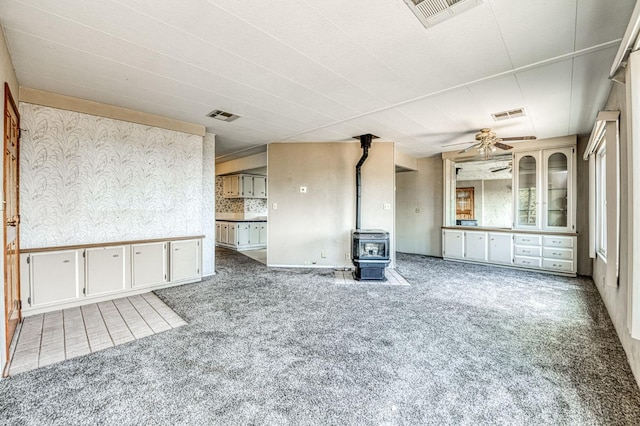 spare room featuring visible vents, a wood stove, and carpet