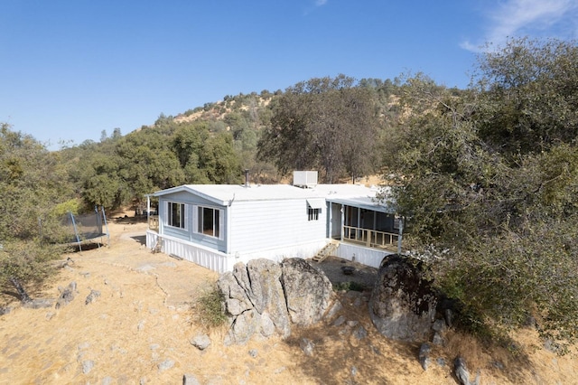 rear view of property with a sunroom and a trampoline