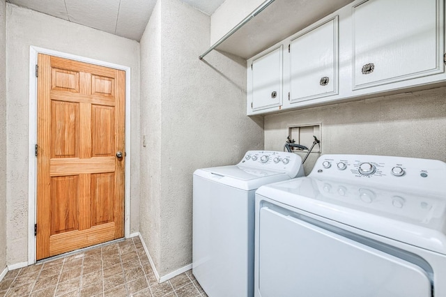 clothes washing area with a textured wall, washer and dryer, baseboards, and cabinet space