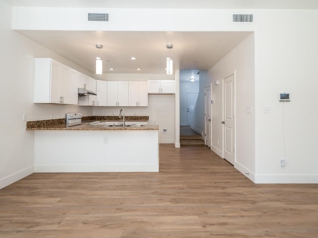 kitchen featuring kitchen peninsula, hanging light fixtures, sink, white cabinetry, and white range