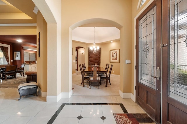 foyer entrance with a chandelier, french doors, light tile patterned floors, and a raised ceiling