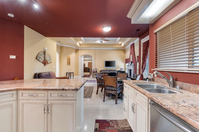 kitchen featuring sink, light stone countertops, ceiling fan, a raised ceiling, and dishwasher