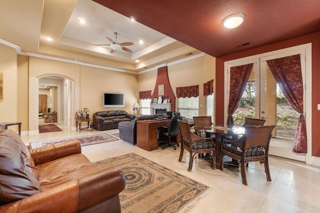 living room featuring a tray ceiling, light tile patterned floors, and ceiling fan