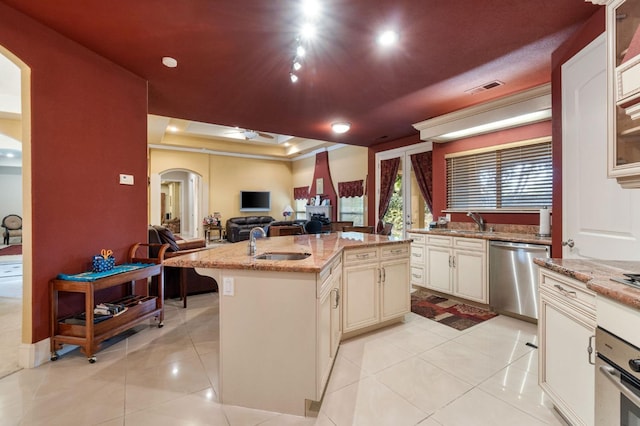 kitchen with a center island with sink, sink, light stone counters, and appliances with stainless steel finishes