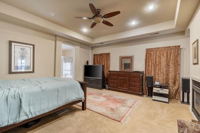 carpeted bedroom featuring a tray ceiling and ceiling fan