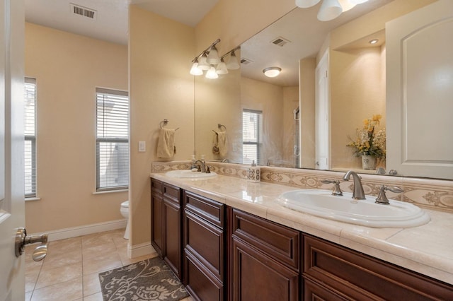 bathroom featuring toilet, vanity, a wealth of natural light, and tile patterned floors