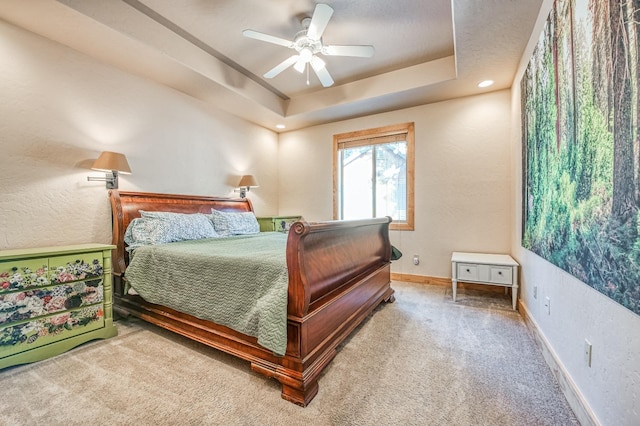 carpeted bedroom with ceiling fan and a raised ceiling