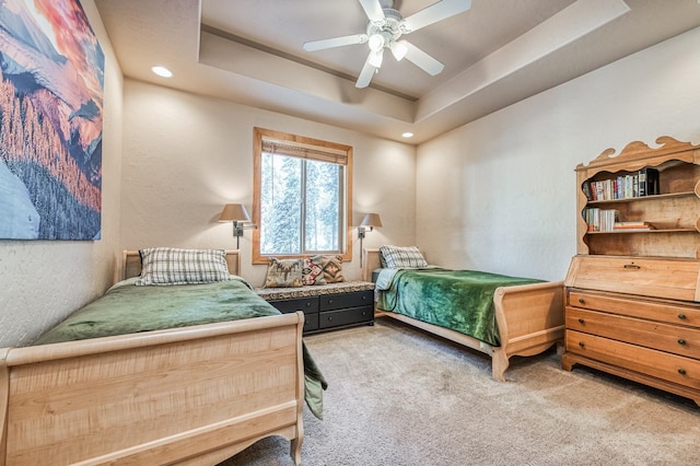 carpeted bedroom featuring a tray ceiling and ceiling fan