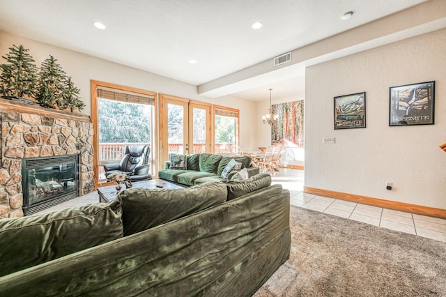 living room with a stone fireplace, carpet floors, and a chandelier