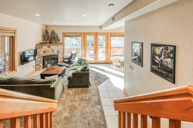 living room featuring light tile patterned flooring, a stone fireplace, a textured ceiling, and french doors