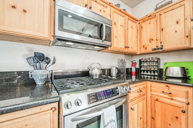 kitchen featuring dark stone countertops, light brown cabinetry, and appliances with stainless steel finishes