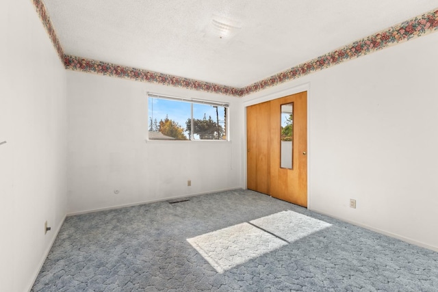 carpeted spare room featuring a textured ceiling