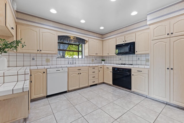 kitchen featuring light tile patterned flooring, tile counters, decorative backsplash, and black appliances