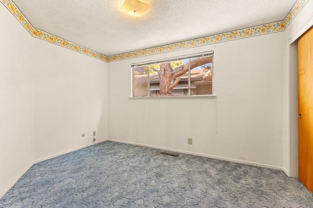 spare room featuring a textured ceiling and carpet