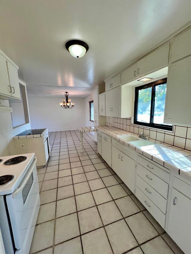 kitchen featuring white range with electric cooktop, sink, decorative backsplash, tile counters, and white cabinetry