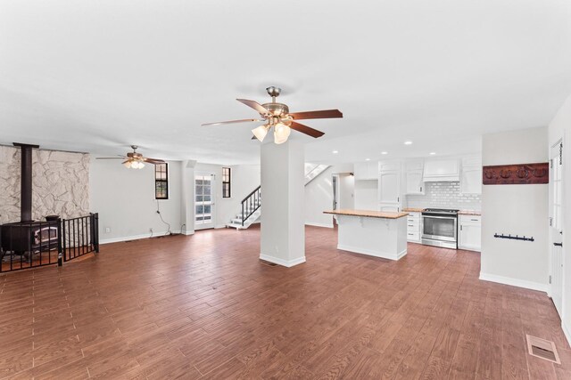 unfurnished living room featuring ceiling fan, a wood stove, and hardwood / wood-style flooring