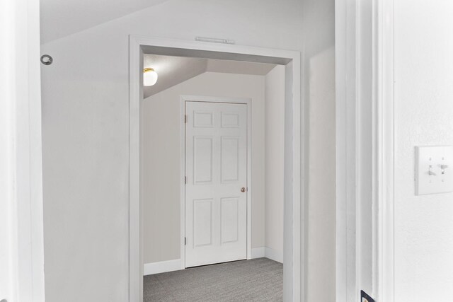 hallway with vaulted ceiling and carpet