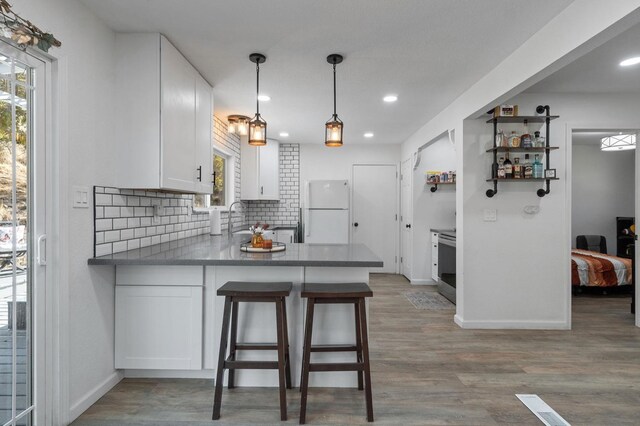 kitchen featuring kitchen peninsula, a wealth of natural light, white cabinets, and white refrigerator