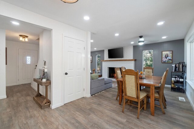 dining area featuring a brick fireplace and hardwood / wood-style flooring