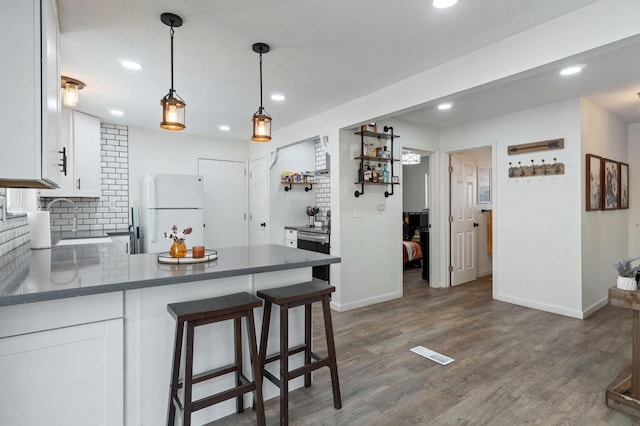 kitchen featuring white cabinetry, sink, dark wood-type flooring, white fridge, and decorative light fixtures