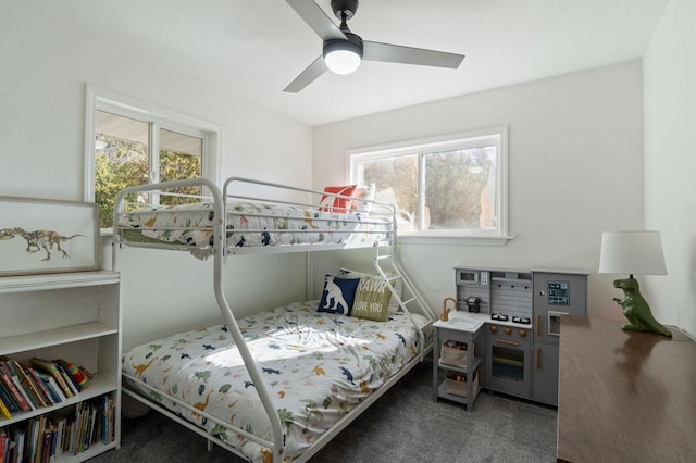 bedroom featuring ceiling fan, multiple windows, and dark colored carpet