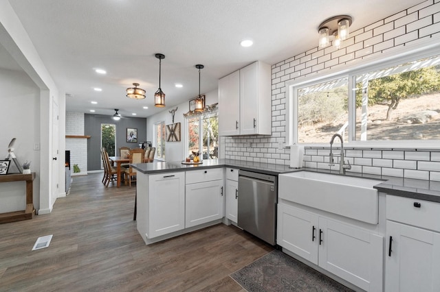 kitchen with white cabinets, sink, stainless steel dishwasher, kitchen peninsula, and a healthy amount of sunlight